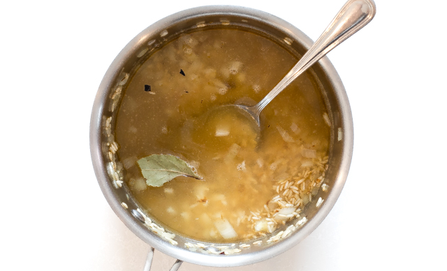 adding broth and bay leaves to pot